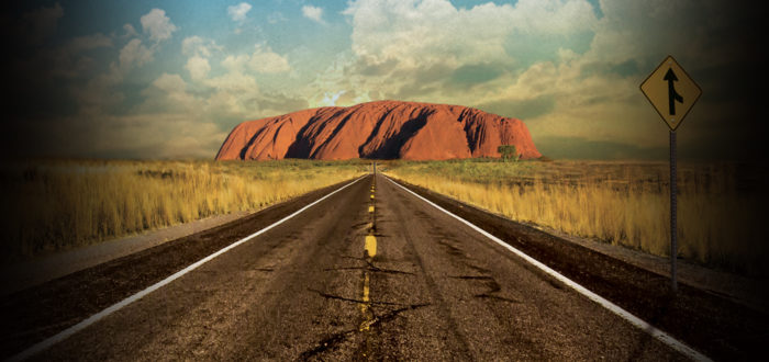 Couverture du livre où une femme laisse partir son homme montrant une route goudronnée menant à Ayers Rock en Australie, dans un ciel bleu et nuageux